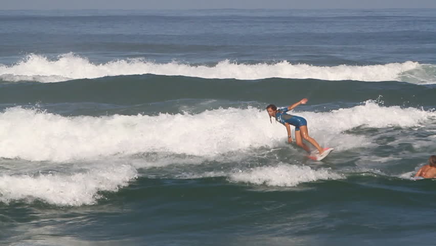A female surfer carving while riding a wave during daytime | Shutterstock HD Video #8300941