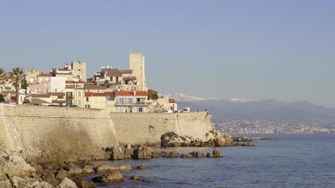 Establishing shot of Antibes on the Mediterranean sea, cote d'Azur, France. View of the old town and ramparts with snow-capped mountains (Alps) in the background. Clear blue sky, sunny winter's day.
