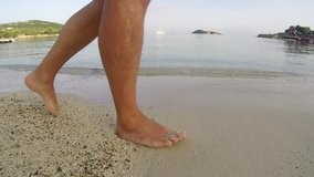 Legs feet Hispanic men walking barefoot on wet sand island beach, steadycam side shoot Stock video