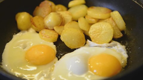 fried eggs and fried potatoes in a pan