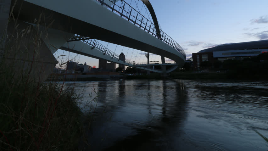 Time lapse of pedestrians walking on bridge over river in downtown Des Moines, Iowa
