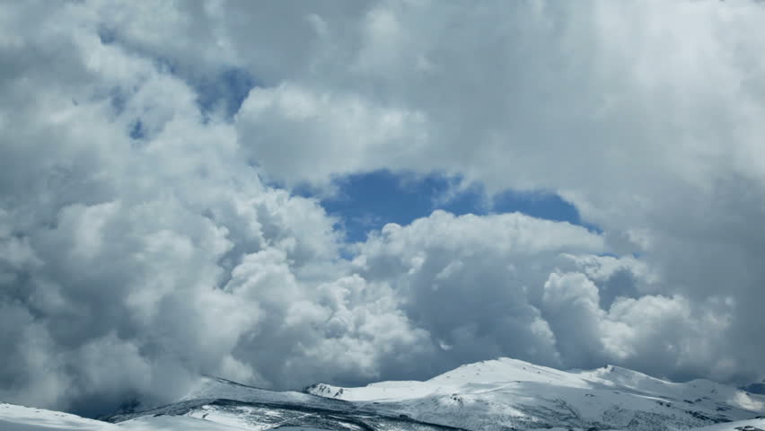 Stormy time lapse clouds on top of snowy mountain