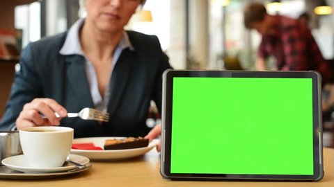 tablet green screen - woman eats cake and drinks coffee in cafe 