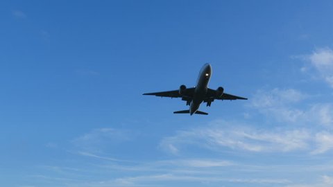 Low angle view of a modern jet landing flying directly above for landing in blue skies.