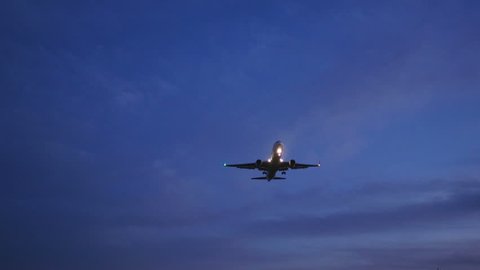 (WITH SOUND) Low angle view of a modern jet landing directly above in twilight skies.