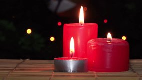 Red Christmas Candles burn against Christmas Tree with Garland Lights. 4K Ultra HD 3840x2160 Video Clip