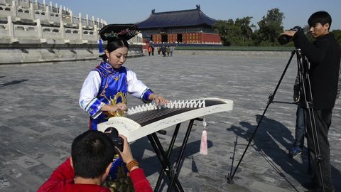 Beijing, China - October 14, 2014: A woman dressed in ancient chinese clothing playing the guzheng. Located in The Temple of Heaven, Beijing, China.