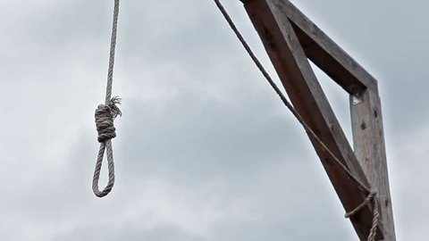 Gallows with swinging noose rope against cloud sky