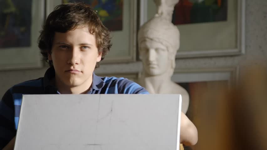 Young art student explains something using canvas