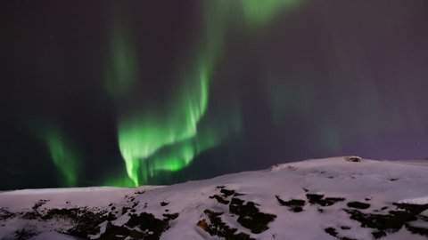 Brilliant active northern lights aurora starry night over snow and rocks