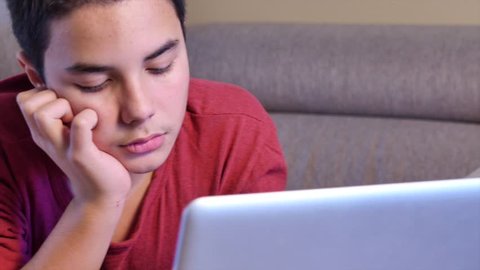 Young teen playing with a computer on a sofa