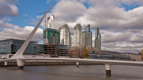 Puente de la Mujer, a modern footbridge and landmark of Buenos Aires, Arg, in front of office buildings. Photo time-lapse with sunlight "flashing" through dark clouds (C. 40D, DSLR).  Stock Video