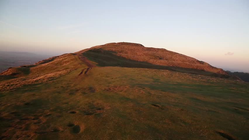 A winters golden sunset on British Camp, Malvern Hills, Herefordshire, with walkers in the distance.