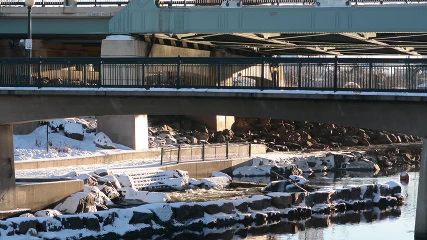 Pedestrian and bike crossing a bridge above the river