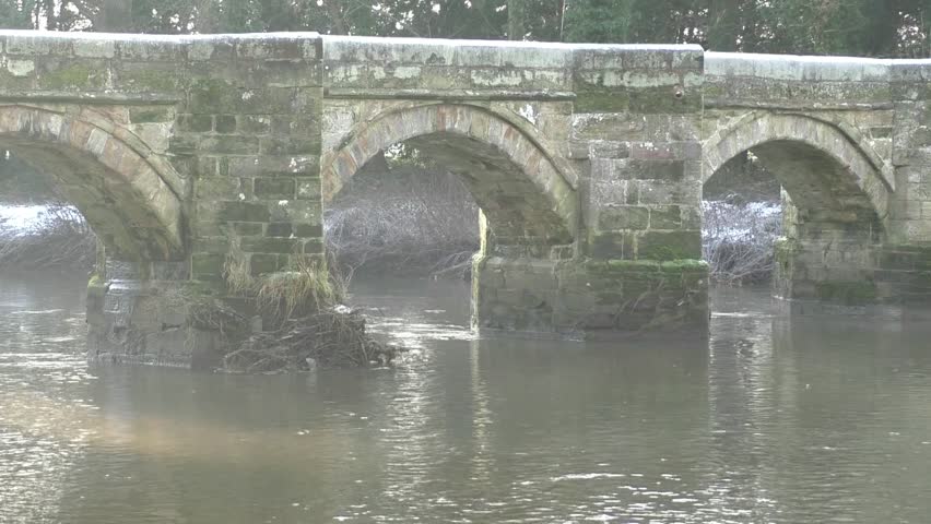 Essex Bridge leading to the Shugborough estate.  Built around 1550 by the Earl of Essex for the Queen I. Grade 1 listed structure.  View of bridge through the trees lit by the winter sun.