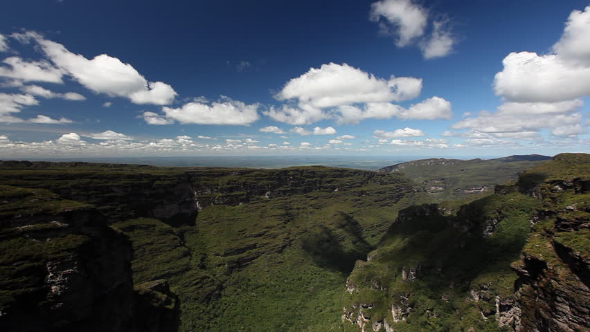 Time lapse of clouds moving over deep and wide canyon with green forests and