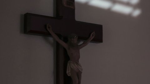 Crucifix on wall of Jesus on the cross as sunlight moves during day