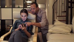 Young couple watching something on smartphone at home at night
