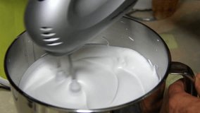 HD Video of whipping cream or egg whites in metal bowl with electric mixer machine