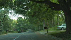 Driving plate: front view, through windshield, upscale 1950s-era homes in an affluent Mid West US neighborhood.  Intended for compositing.  24mm lens, stabilized clip, slow speed, recorded in 4K, UHD