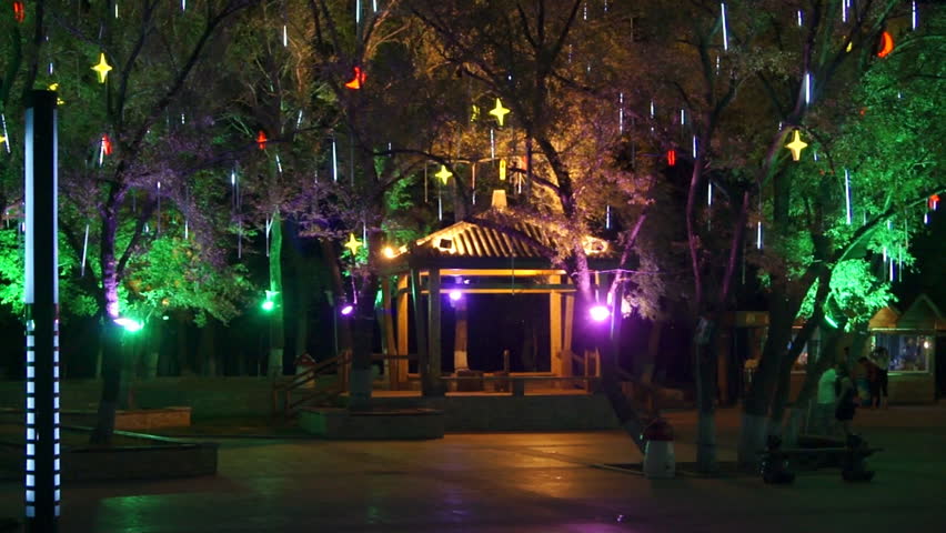 Heihe City Heilongjiang Park Night View 02. Chinese border town of Heihe, Heilongjiang public park at night. Trees lighted by lamps, resting people walking.