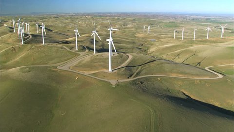 Low aerial view of cluster of wind turbines in green hillside