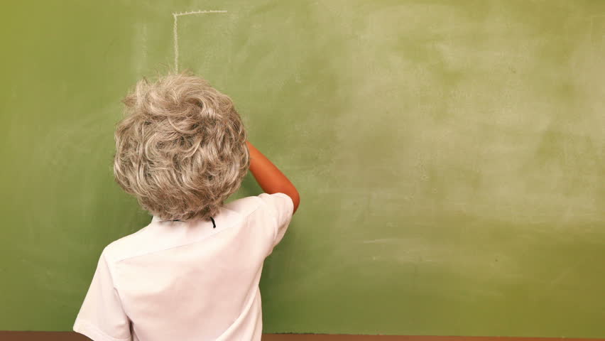 Rear view of cute pupil writing maths on chalkboard at the elementary school