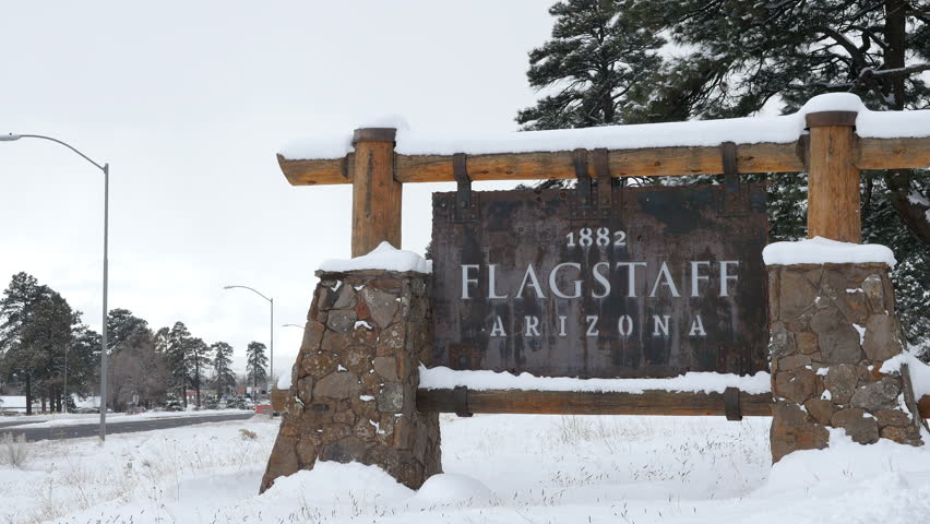The sign at the city limits of Flagstaff, Arizona in a snowstorm, with traffic passing. 4K UHD. 3840x2160