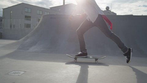 SLOW MOTION: Skateboarder riding and jumping in a skate park
