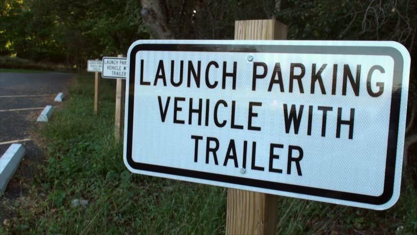 "Launch parking vehicle with trailer" sign at small lake.
