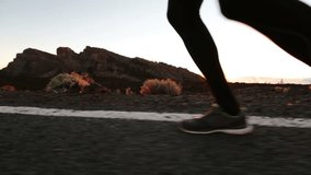 Running shoes and legs in action closeup. Male runner jogging on road. Man training at sunset at mountain road. Exercise and healthy lifestyle video.