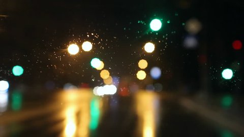 Bad weather, rain and wet snow on the road. Night driving, the road in the headlights of a car window, rain drops and wet snow on the windshield. Bokeh and glare,   traffic in poor visibility