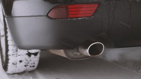 Exhaust pipe of a running car at winter. Car fumes closeup.
