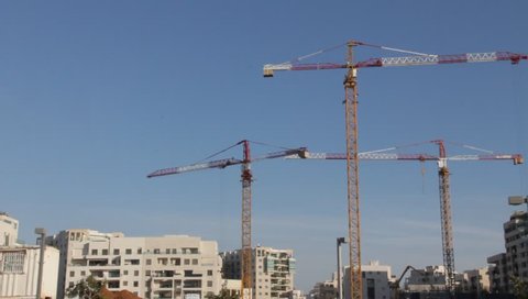 TEL AVIV, ISRAEL – SEPTEMBER 18: Tower cranes working  on the construction of an apartment house  on September18, 2014  in Tel Aviv, Israel