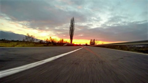 UHD Sport car driving on a country road sunset. Wheel spinning POV - Point of View, sunrise. Trees on the side. Fast motion speed. 4k shoot