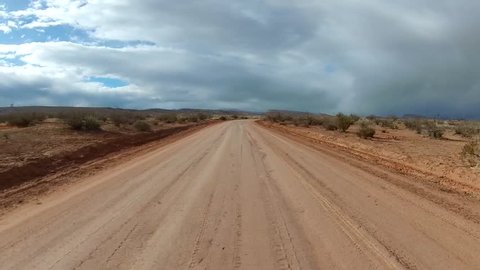 Off-road driving on high-desert road with winter storm in the distance. POV filmed in the desert southwest of St. George, UT along the Arizona border.