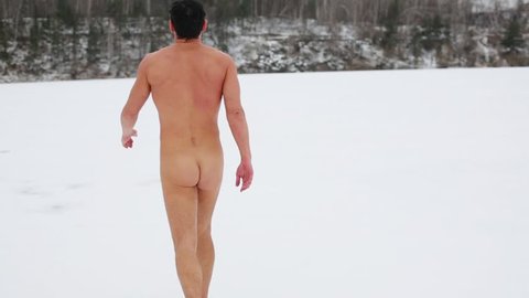 Naked man walking in the winter on snow and spreads hands