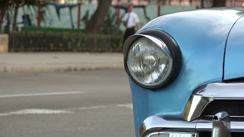 Tourism and travel, Cuba, La Habana, Havana, closeup view of old vintage blue car, with autos passing on the street