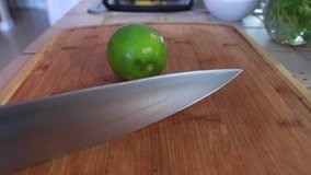 Female hands cutting a green lime with a big knife