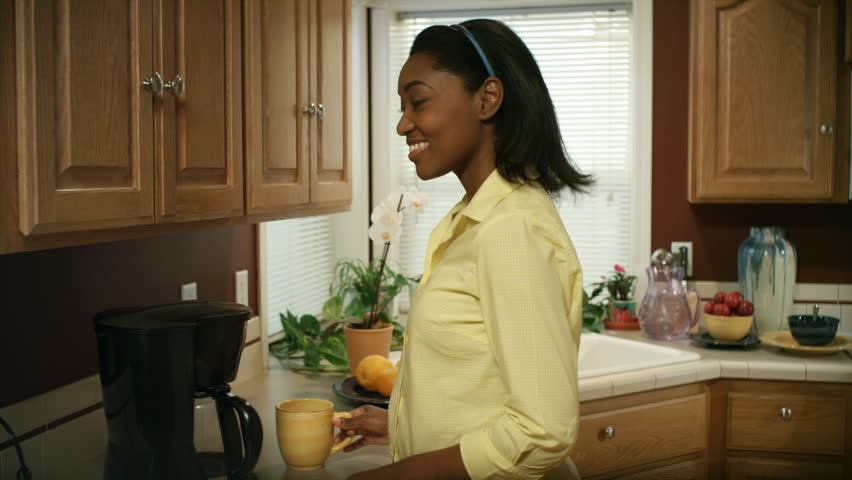 An African American woman performs various tasks around the house. 