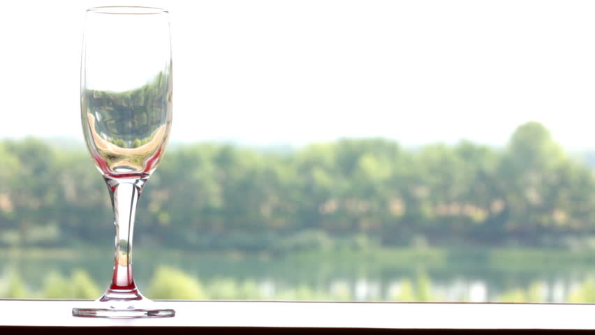 glass filled with red wine on summer landscape background