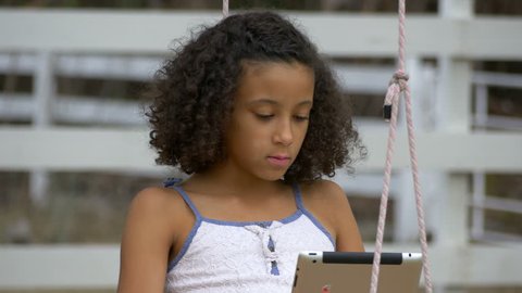 Young Girl on a Swing with a Tablet