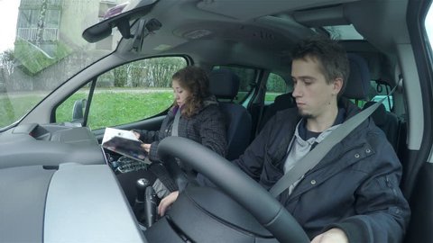 Man in car picks up the phone while driving 4K. Fisheye front side view of driver and passenger in car while traveling to location. Dressed in warm jackets.