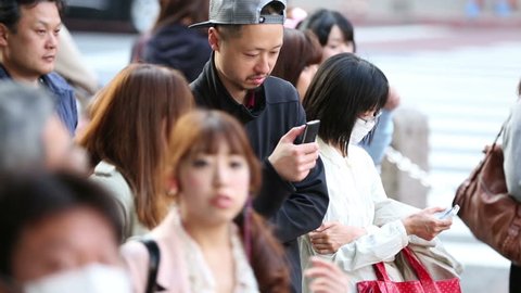 TOKYO, JAPAN - CIRCA 2013: People browsing the internet while waiting to cross a busy intersection Editorial Stock Video