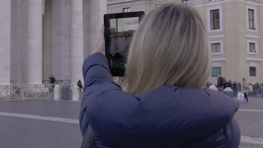 young woman is making photos to St. Peter church with tablet pc: tourism in Rome