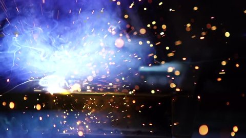 Flashes and lot of sparks from welding work at construction site in dark in slow motion
