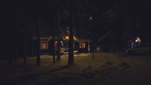 POV. Cozy wooden house in winter forest, at night, Finland.