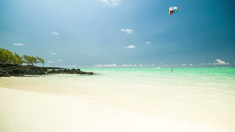 Tropical beach and a paraglider over the waters in the distance. Horizon over water. 