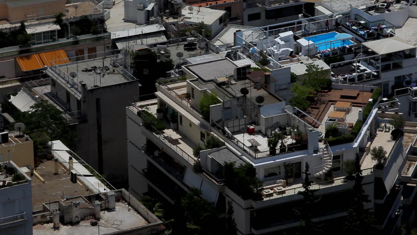 Buildings in Athens from above. we can see people walking around a pool which is