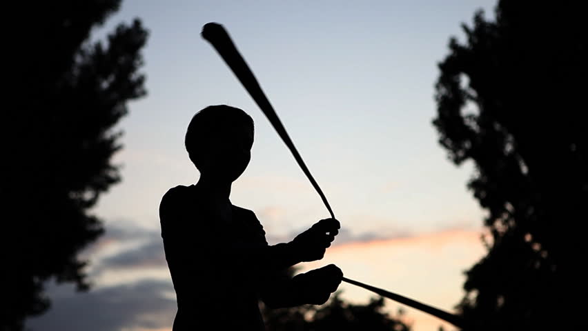 Silhouette of young girl playing poi in the park 